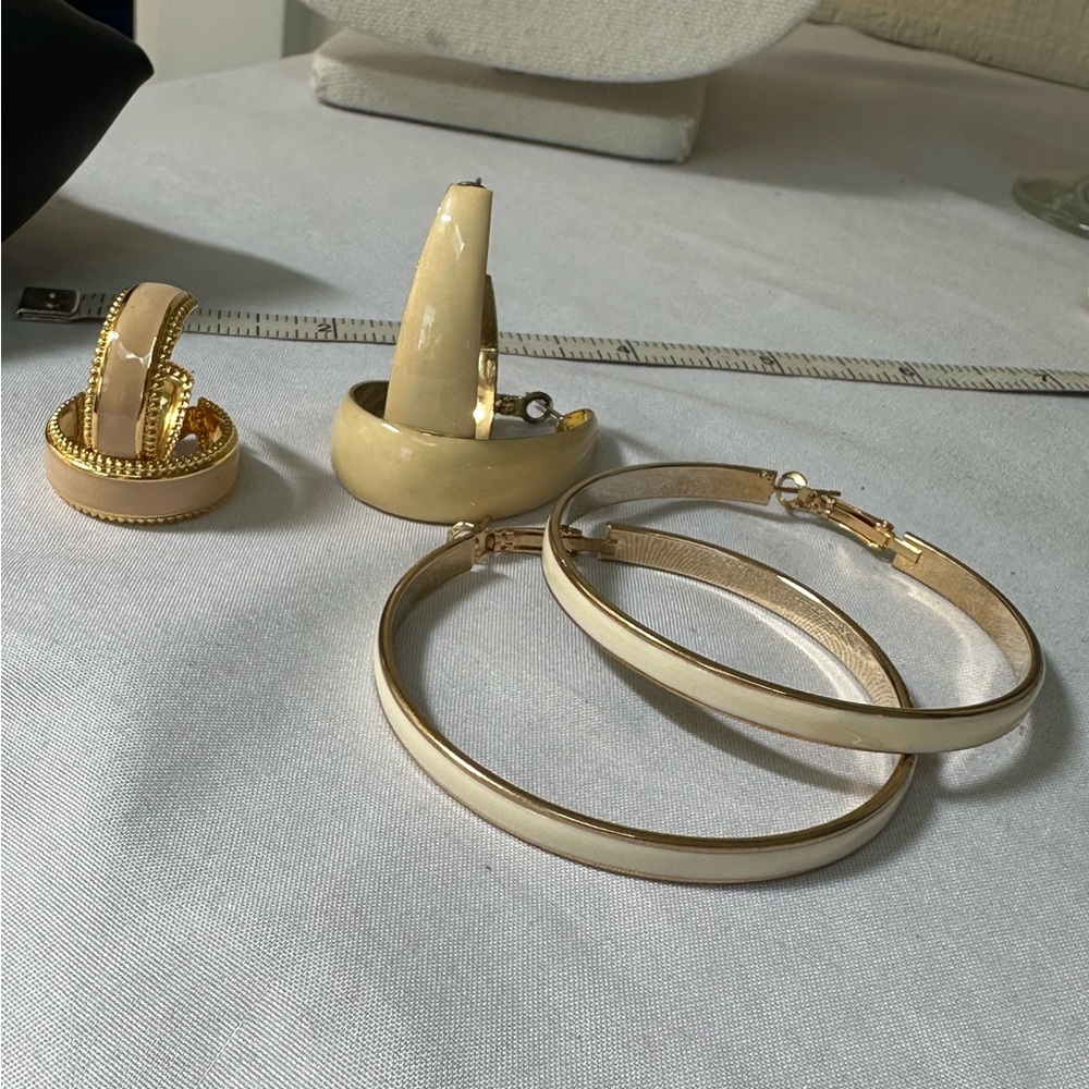 Three pair of beige and goldtone hoop earrings